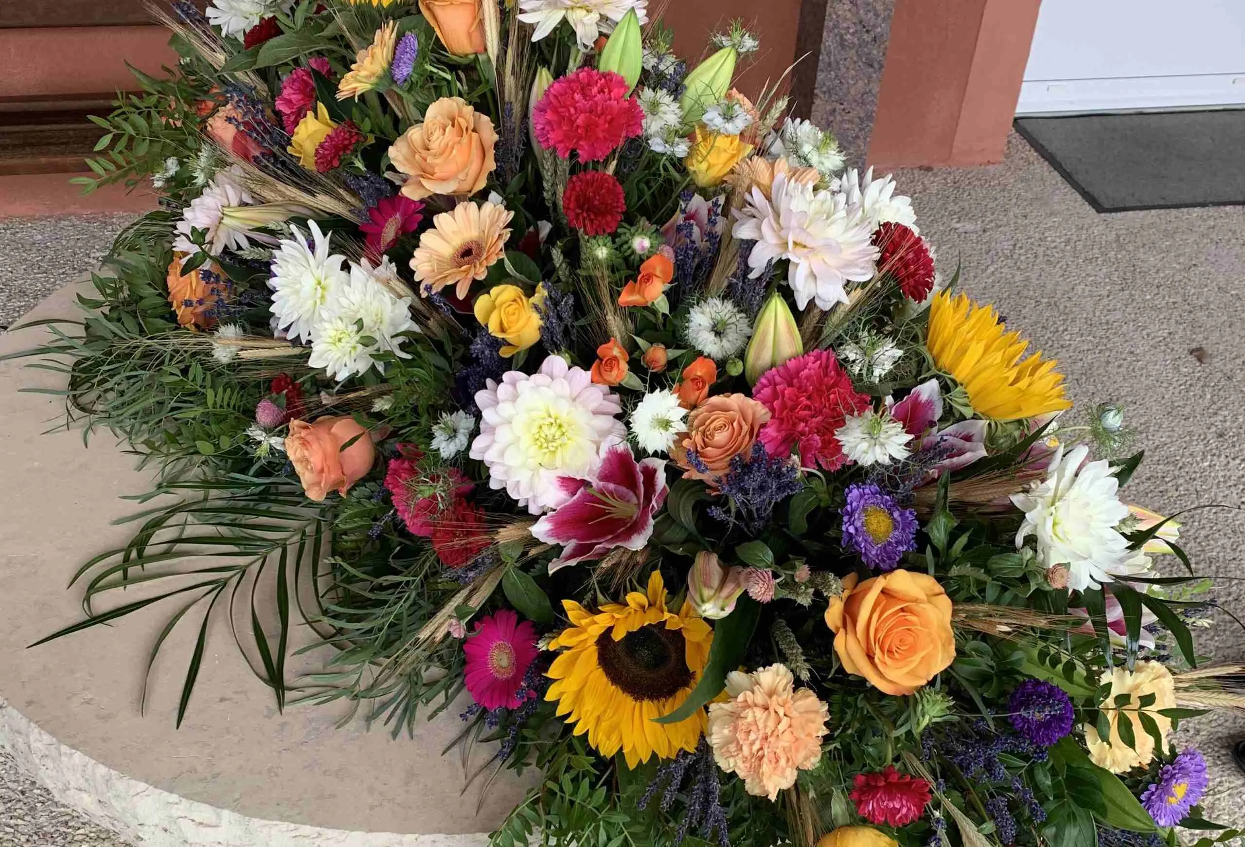 Grand et riche bouquet de fleurs de deuil multicolores avec des roses, des tournesols et des lys